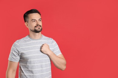 Photo of Man making promise on red background, space for text. Oath gesture