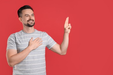 Photo of Man showing oath gesture on red background, space for text. Making promise