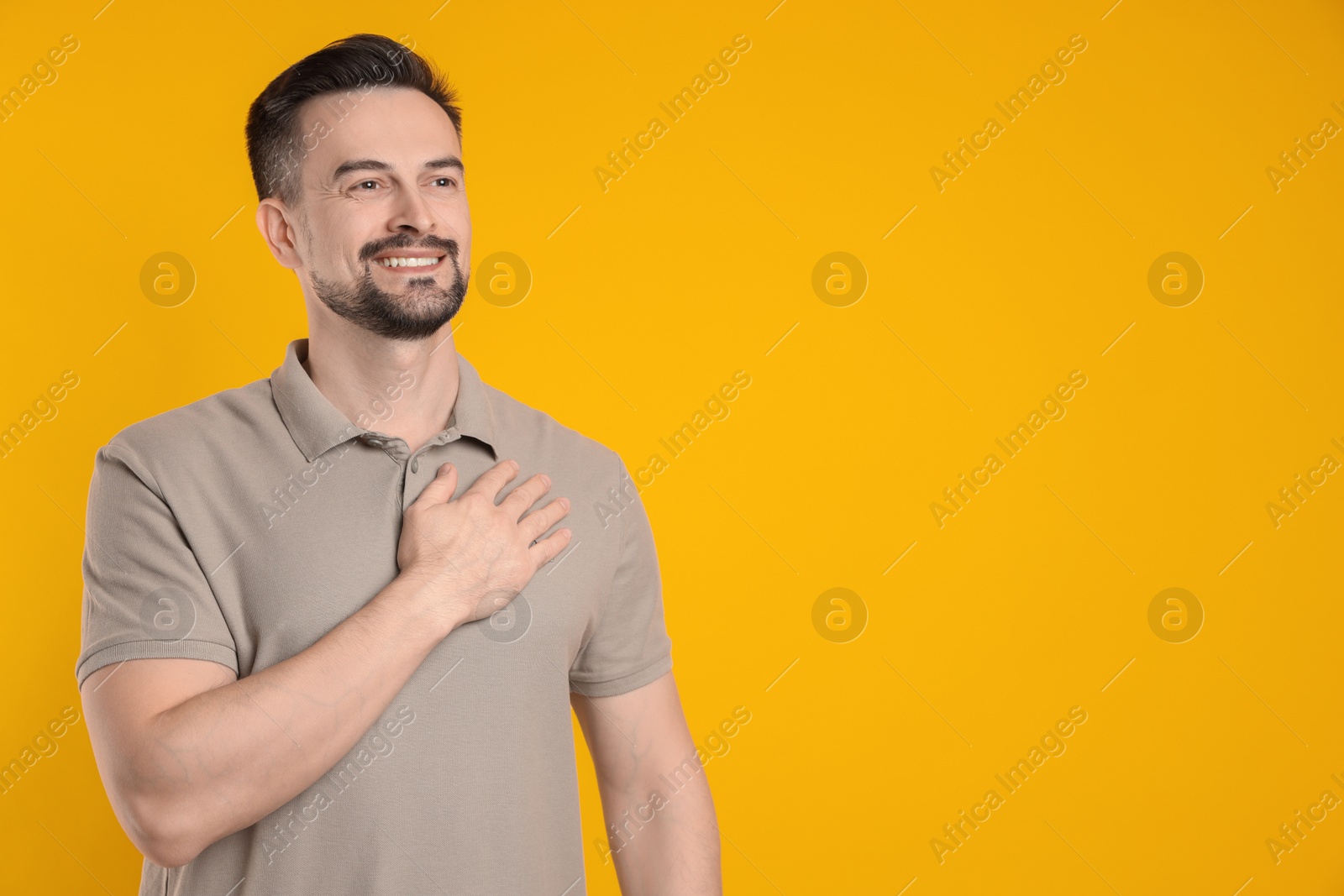 Photo of Man making promise on orange background, space for text. Oath gesture