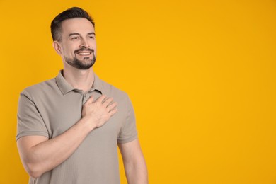 Photo of Man making promise on orange background, space for text. Oath gesture