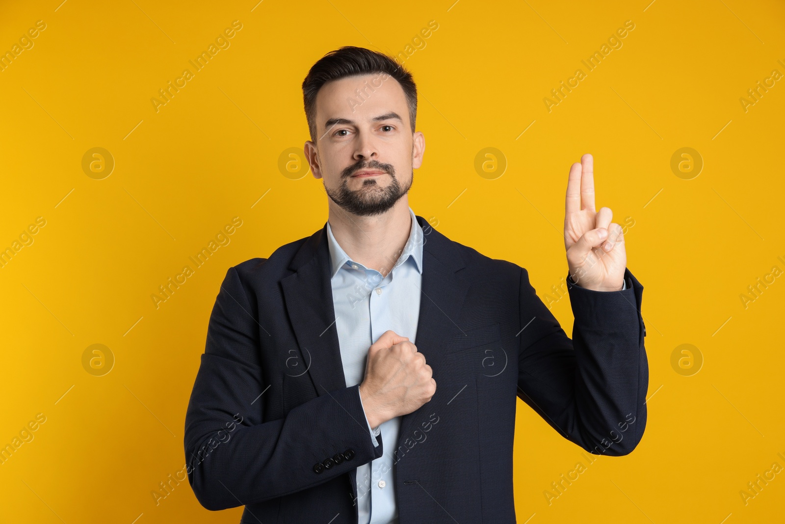 Photo of Man showing oath gesture on orange background. Making promise