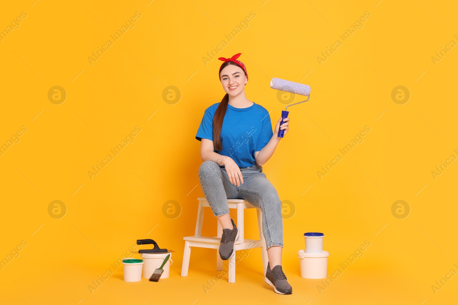 Photo of Young decorator with different tools on orange background