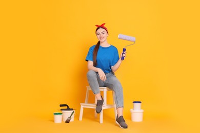 Photo of Young decorator with different tools on orange background