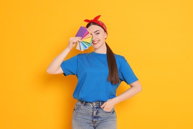 Photo of Portrait of young decorator with color palettes on orange background