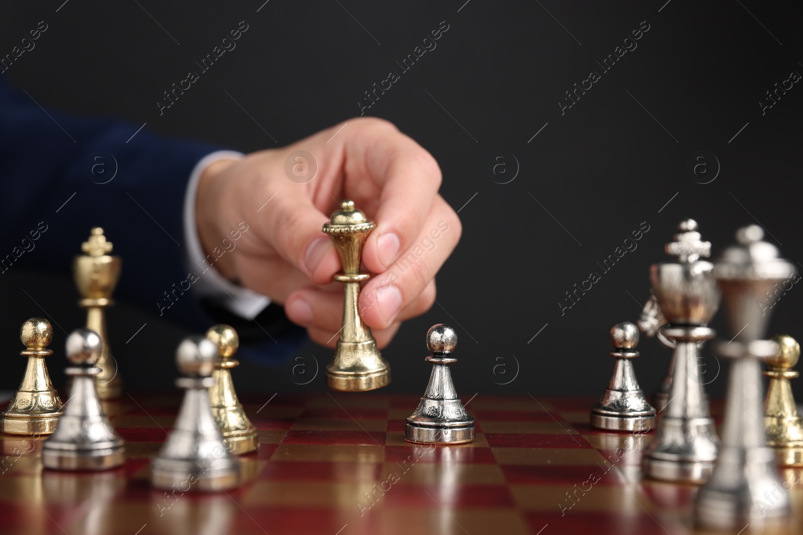 Photo of Businessman playing chess on chessboard against black background, closeup. Competition concept