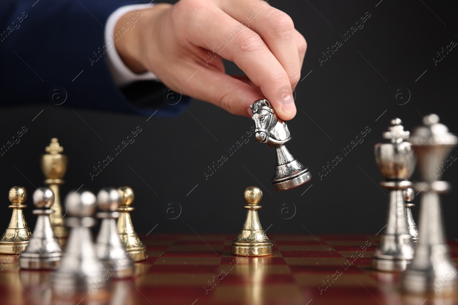 Photo of Businessman playing chess on chessboard against black background, closeup. Competition concept