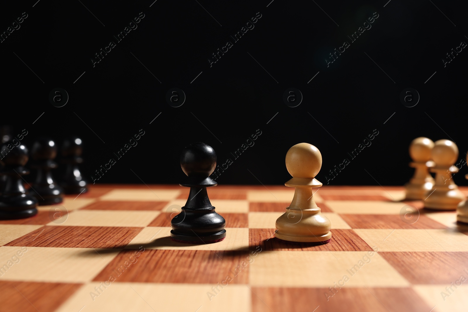 Photo of Black and white pawns near other chess pieces on chessboard. Competition concept