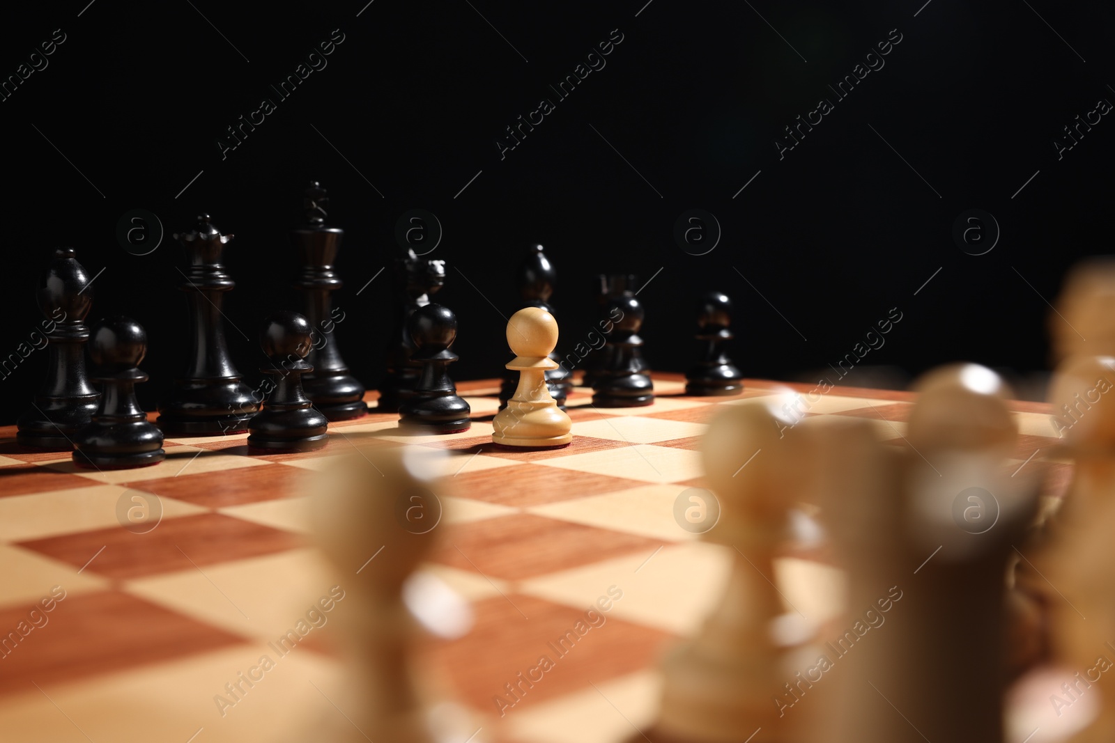 Photo of White pawn in front of other black chess pieces on chessboard, closeup. Competition concept