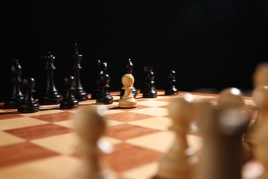 Photo of White pawn in front of other black chess pieces on chessboard, closeup. Competition concept