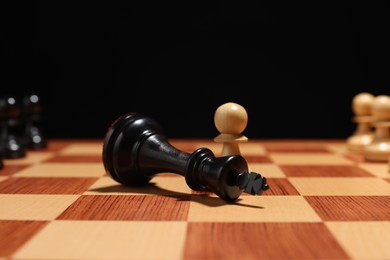 Photo of White pawn near fallen black chess king on chessboard, closeup. Competition concept