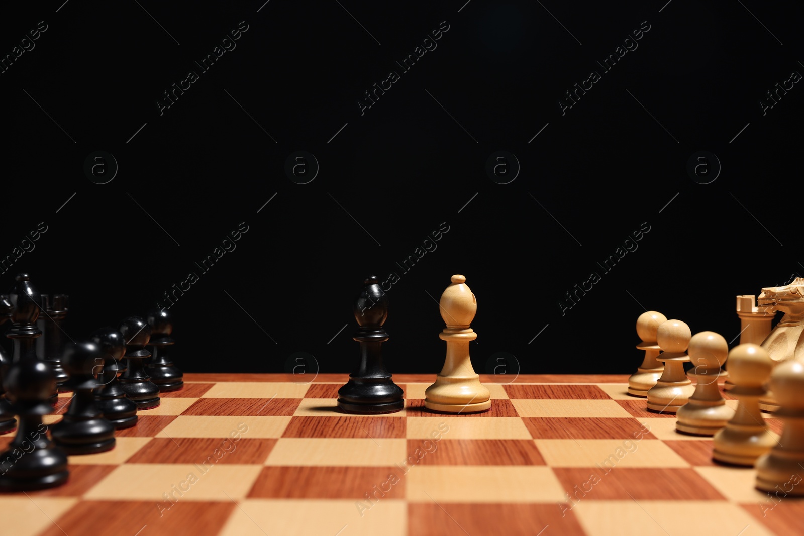 Photo of Black and white bishops near other chess pieces on chessboard, closeup. Competition concept