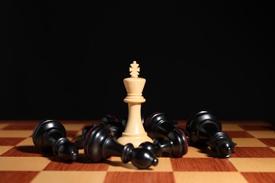 Photo of White chess king among fallen black pieces on chessboard, closeup. Competition concept