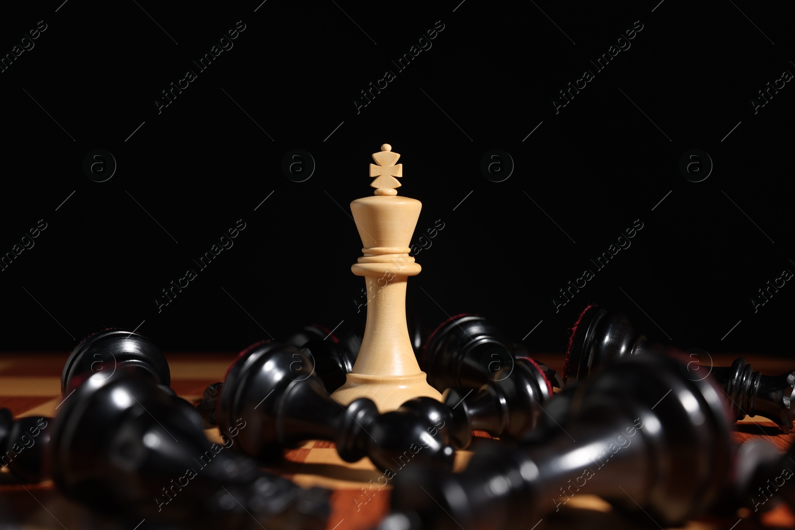 Photo of White chess king among fallen black pieces on chessboard, closeup. Competition concept