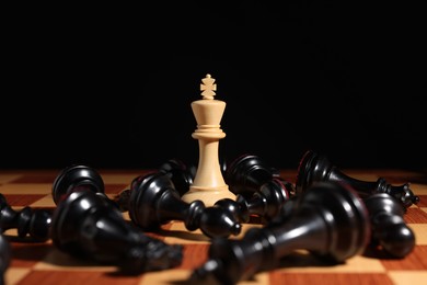 Photo of White chess king among fallen black pieces on chessboard, closeup. Competition concept