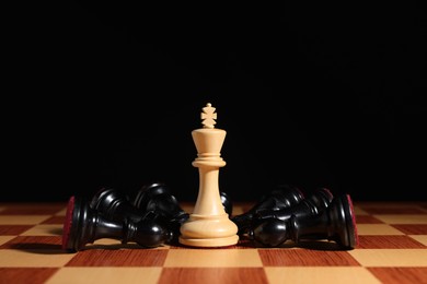 Photo of White chess king among fallen black pieces on chessboard, closeup. Competition concept