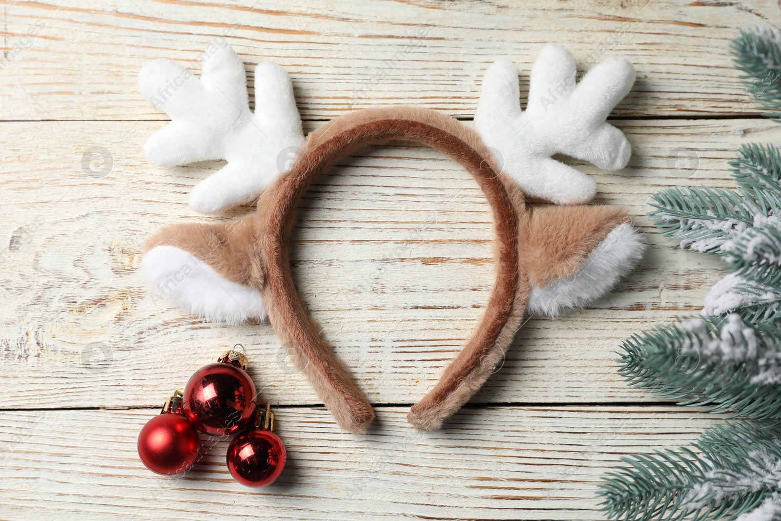 Photo of Beautiful reindeer headband and Christmas decor on white wooden background, flat lay