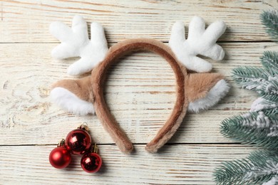 Photo of Beautiful reindeer headband and Christmas decor on white wooden background, flat lay