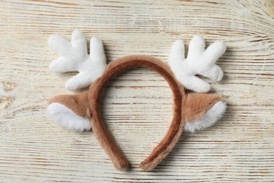 Photo of Beautiful reindeer headband on white wooden background, top view. Christmas accessory