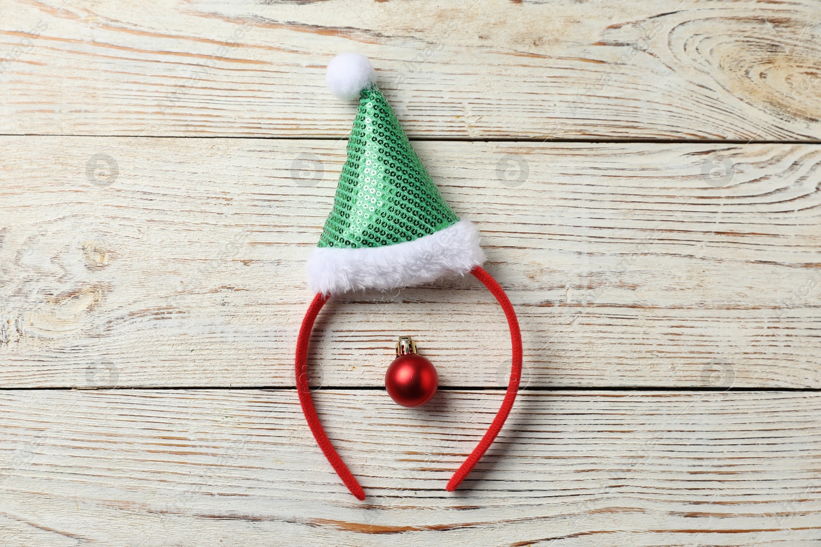 Photo of Stylish party headband and Christmas bauble on white wooden background, top view