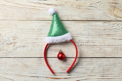 Photo of Stylish party headband and Christmas bauble on white wooden background, top view