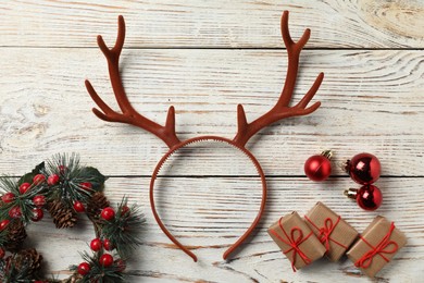 Photo of Beautiful reindeer headband and Christmas decor on white wooden background, flat lay