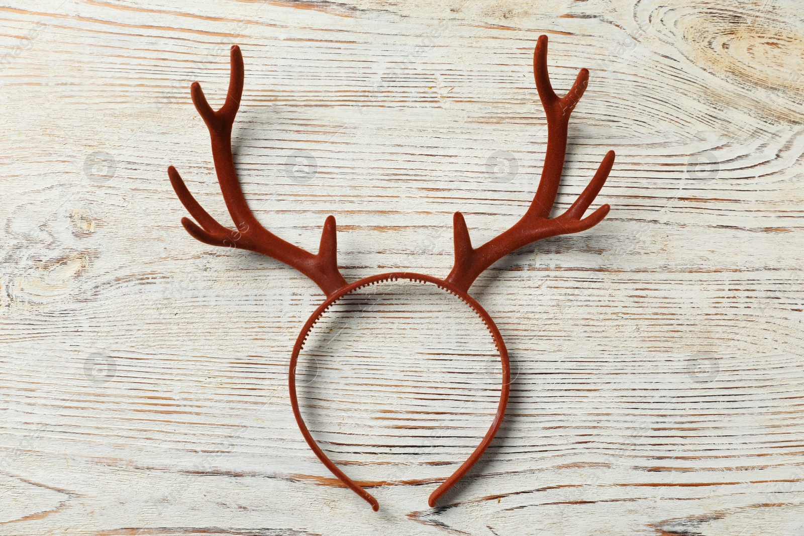 Photo of Beautiful reindeer headband on white wooden background, top view. Christmas accessory