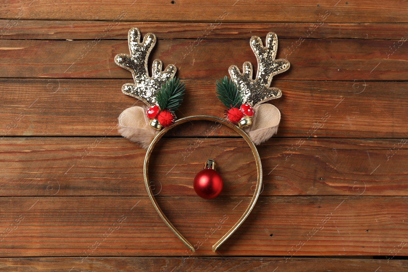 Photo of Beautiful reindeer headband and Christmas bauble on wooden background, top view