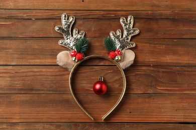 Photo of Beautiful reindeer headband and Christmas bauble on wooden background, top view