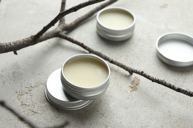 Photo of Natural solid perfume in containers and dry twigs on light table, closeup