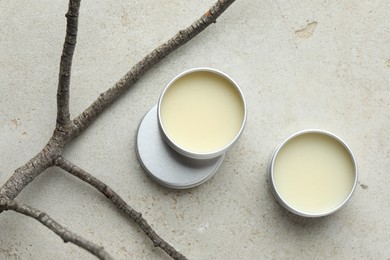 Photo of Natural solid perfume in containers and dry twigs on light table, flat lay