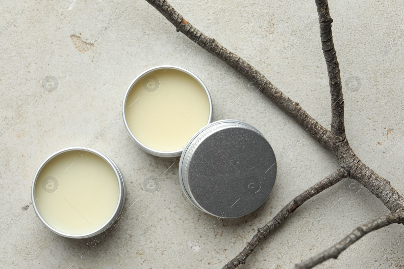 Photo of Natural solid perfume in containers and dry twigs on light table, flat lay