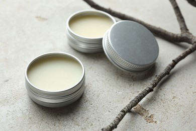 Photo of Natural solid perfume in containers and dry twigs on light table, closeup