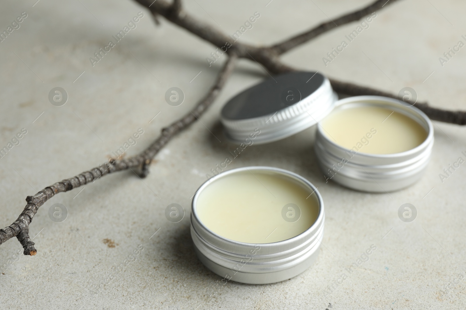 Photo of Natural solid perfume in containers and dry twigs on light table, closeup