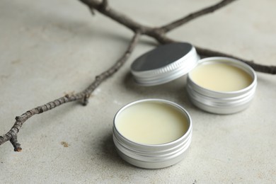 Photo of Natural solid perfume in containers and dry twigs on light table, closeup