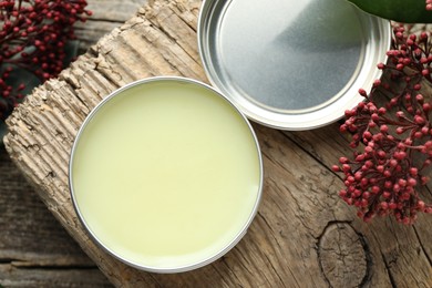 Photo of Natural solid perfume and skimmia plant on wooden table, flat lay