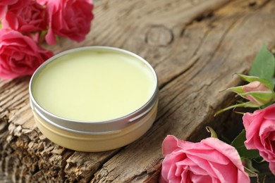 Photo of Natural solid perfume and pink roses on wood, closeup