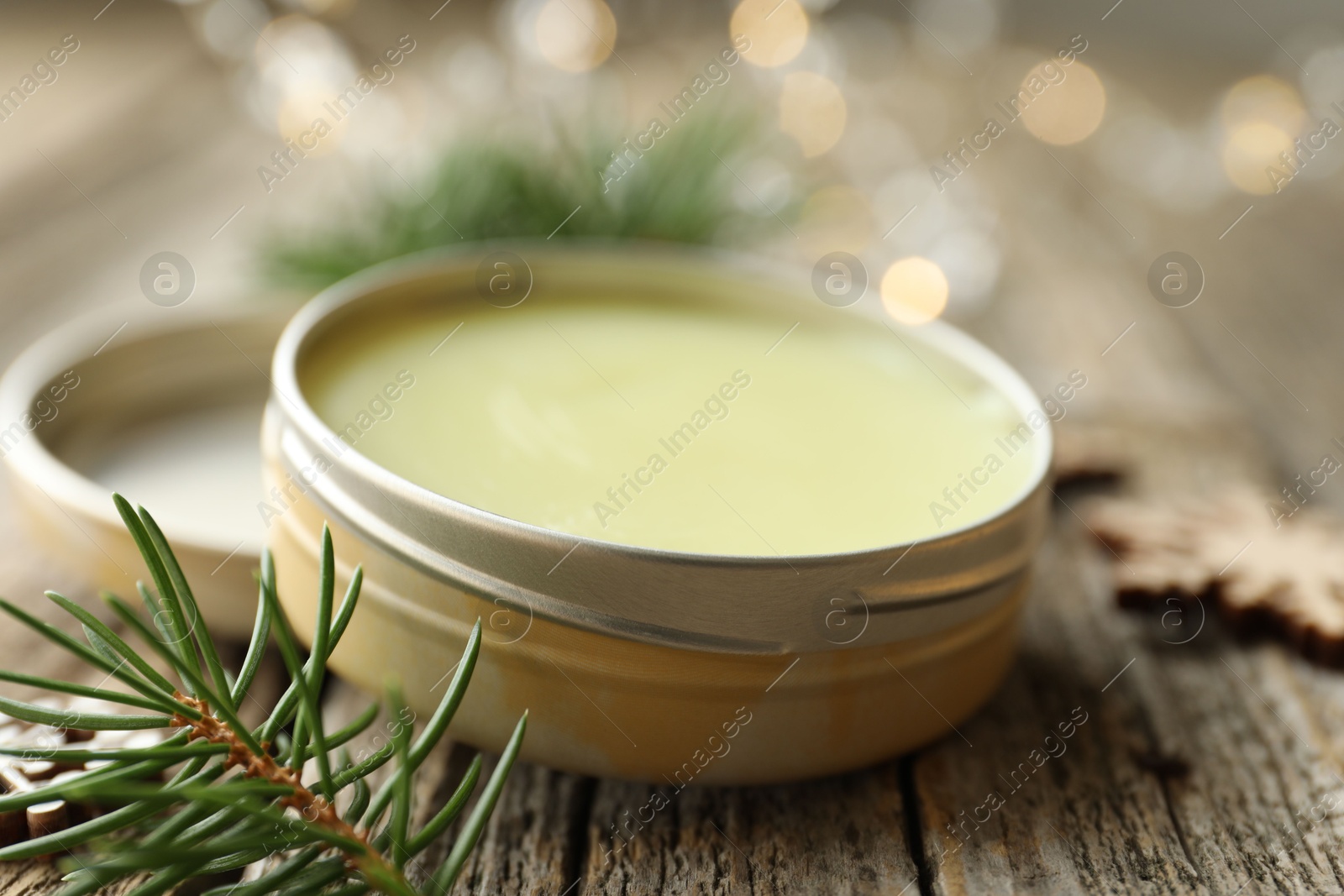 Photo of Natural solid perfume in container and fir on wooden table, closeup