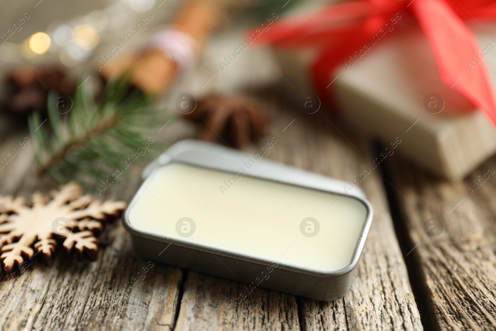 Photo of Natural solid perfume in container and Christmas decor on wooden table, closeup