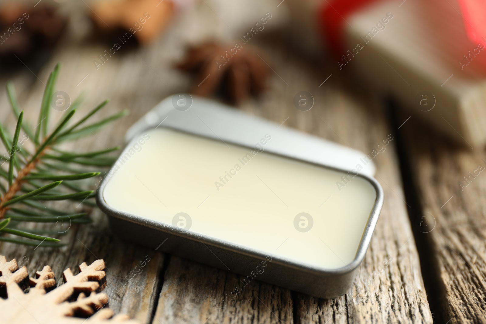 Photo of Natural solid perfume in container and Christmas decor on wooden table, closeup