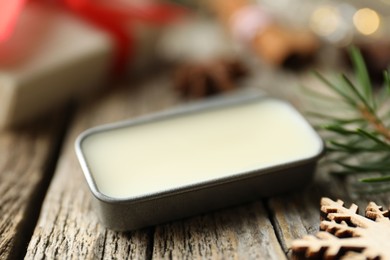 Photo of Natural solid perfume in container and Christmas decor on wooden table, closeup