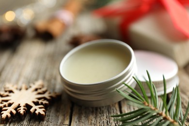 Photo of Natural solid perfume in container and Christmas decor on wooden table, closeup