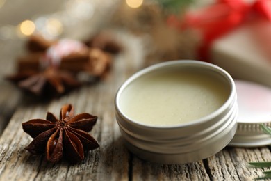 Photo of Natural solid perfume in container and anise star on wooden table, closeup