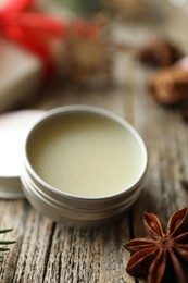 Photo of Natural solid perfume in container and anise star on wooden table, closeup