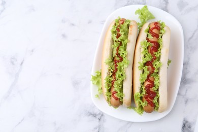 Photo of Tasty hot dogs with lettuce and ketchup on white marble table, top view. Space for text