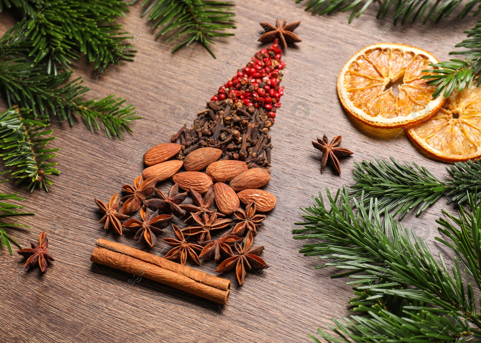 Photo of Christmas tree made of different spices, dried orange slices and fir branches on wooden table