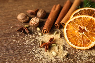 Photo of Different spices, dried orange slices and fir tree branches on wooden table, closeup. Christmas season