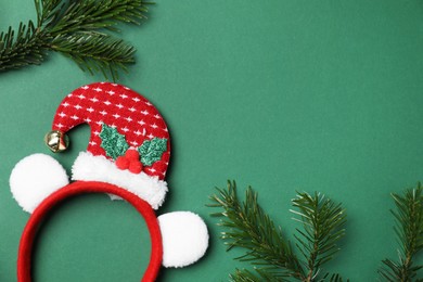 Photo of Stylish party headband and fir branches on green background, top view with space for text. Christmas accessory