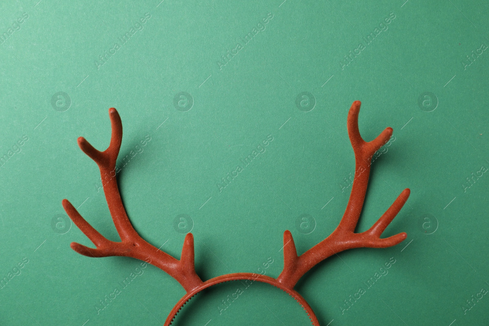 Photo of Beautiful reindeer headband on green background, top view with space for text. Christmas accessory