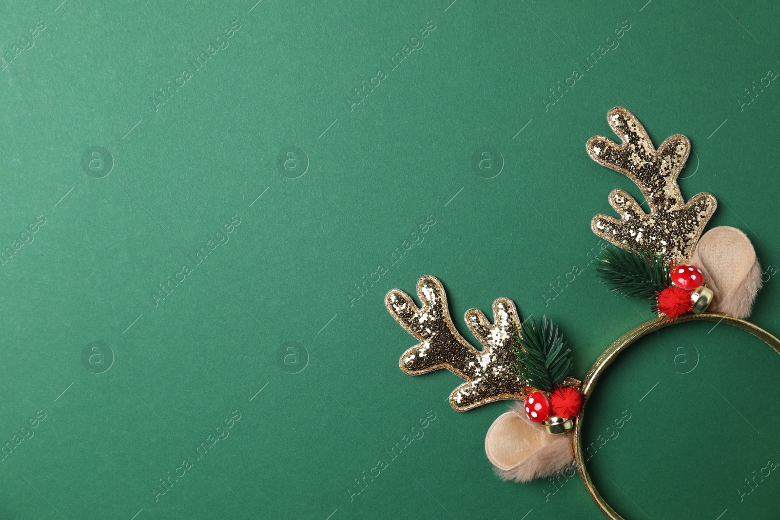 Photo of Beautiful reindeer headband on green background, top view with space for text. Christmas accessory