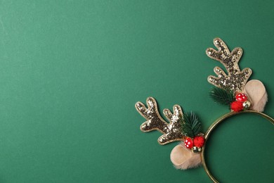 Photo of Beautiful reindeer headband on green background, top view with space for text. Christmas accessory